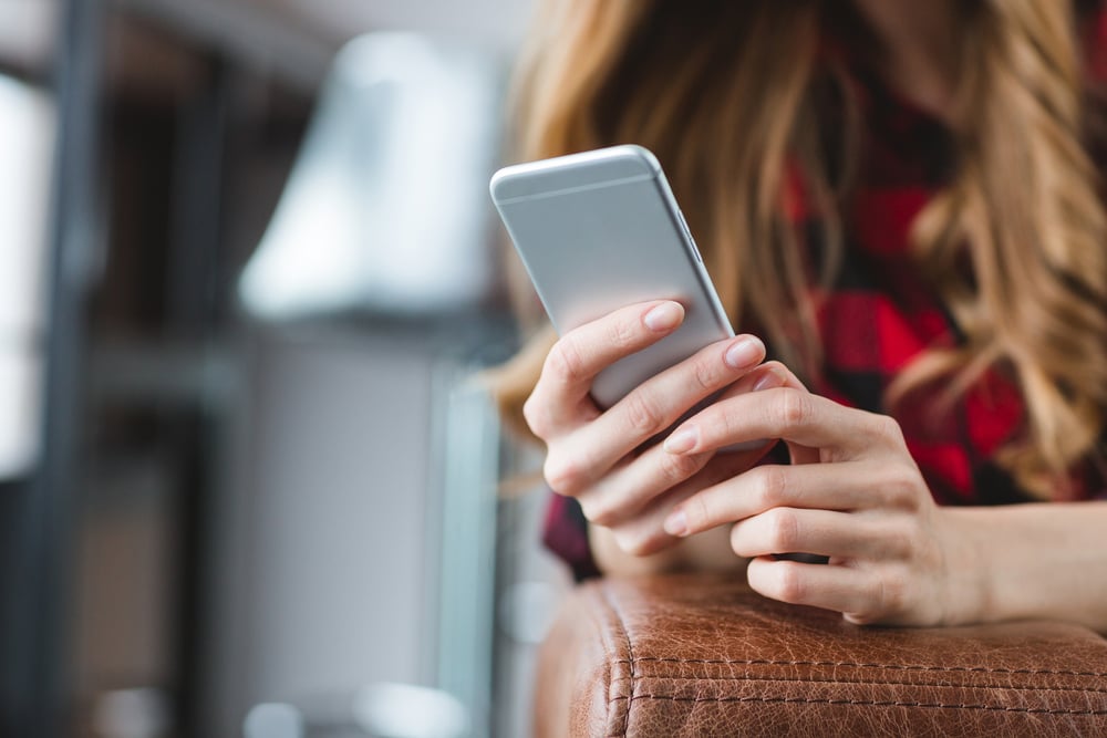 Close up of smartphone used by young blonde woman in plaid shirt-1
