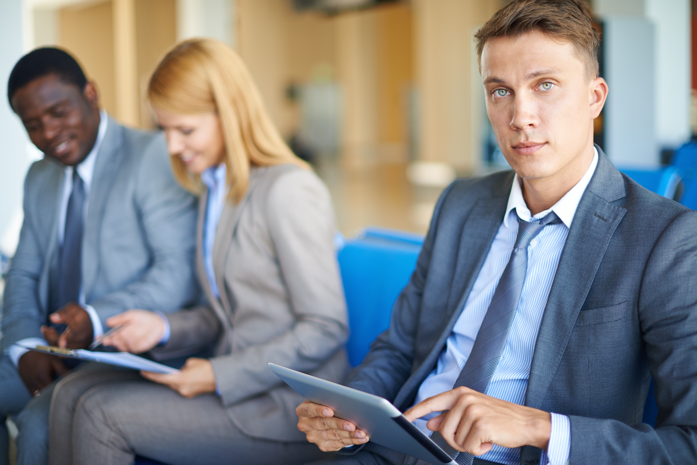man on tablet looking at camera wiht 2 people in background-1